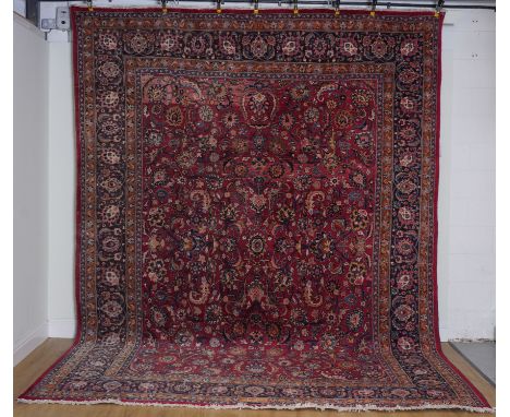 A MASHAAD CARPET, PERSIANThe burgundy field with an allover design of palmettes, serrated leaves and floral sprays, a dark in