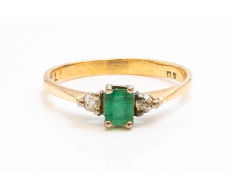 AN 18CT GOLD, EMERALD AND DIAMOND THREE STONE RINGClaw set with the rectangular cut emerald between two circular cut diamonds