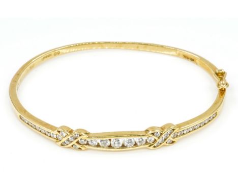 AN 18CT GOLD AND DIAMOND OVAL HINGED BANGLEThe front mounted with circular cut diamonds and with two X shaped motifs, detaile