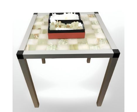 An onyx and aluminium chessboard table, width 42 cm, and a set of polished onyx chess pieces, kings 7.5 cm.