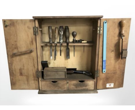 A wall mounted tool cabinet containing carpentry chisels, other tools etc, cabinet 45 cm wide