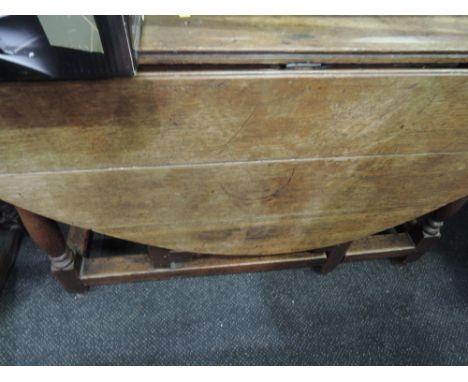 A late 19th century oak dining table in the 18th century style having drop leaf top with frieze drawer on turned gate legs 