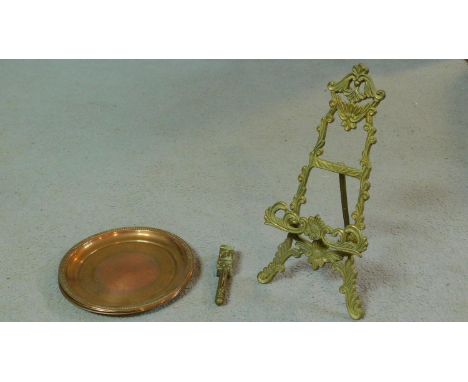 An antique brass easel with foliate design along with three engraved copper trays with dragooned edges and an antique brass W