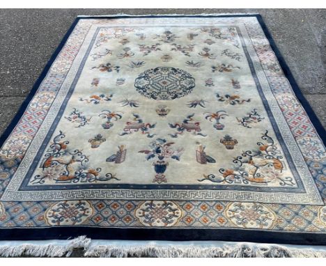 A large beige ground rug with a blue border and central medallion 276cm x 386cm 