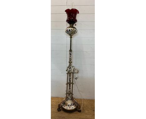 A converted floor standing oil lamp with a painted ceramic bowl and centre pole with a brass twisted outer frame terminating 