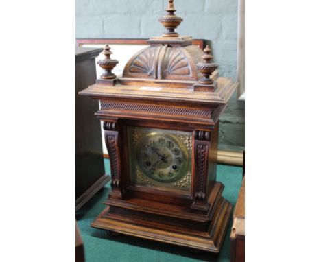 A carved mahogany striking mantel clock with brass dial