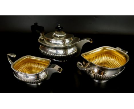 A George III silver three piece tea set, of rectangular form with part fluted body, engraved with a dragon crest, the teapot 