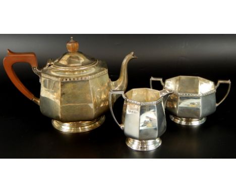 A George V Art Deco silver three piece tea service, comprising teapot, 16cm high, with ebonised handle and octagonal knop, wi