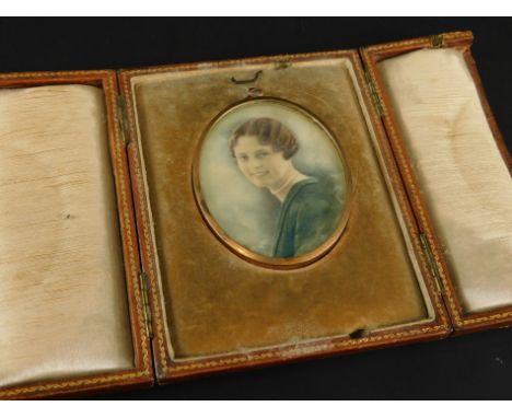 An early 20thC miniature on ivorine, depicting a lady wearing a pearl necklace and a green jacket, painted, but from a photog