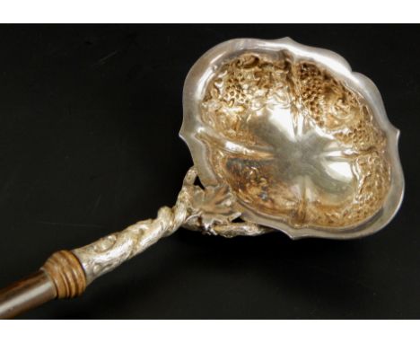 A Georgian style white metal punch ladle, the body with berries and leaves, unmarked on a turned rosewood handle, 41cm long. 