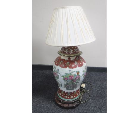 A Chinese floral pottery table lamp with shade on wooden base 