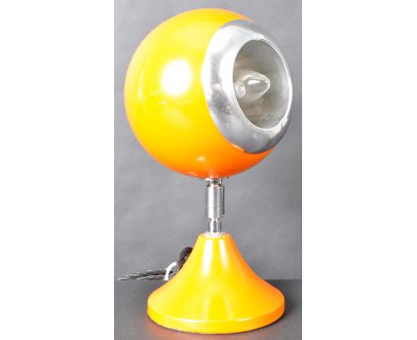 A 1970s Vintage Space Age Eyeball Lamp with a chrome rim and cup, supported on a 360 swivel articulated arm, on a orange shap