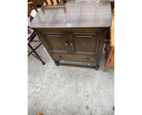 A SMALL ERCOL TWO DOOR CABINET WITH SINGLE DRAWER ON OPEN BASE, 31" WIDE 