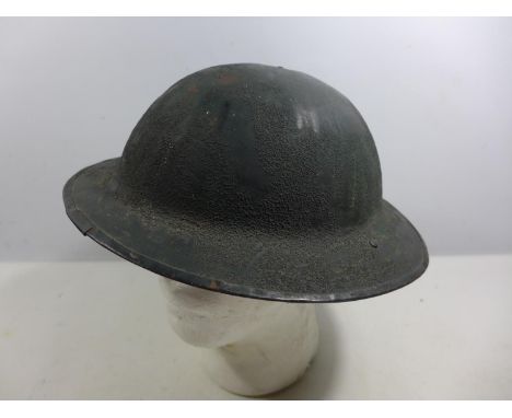 A BRITISH ARMY EARLY TO MID 20TH CENTURY GREEN PAINTED STEEL HELMET WITH LEATHER LINING 
