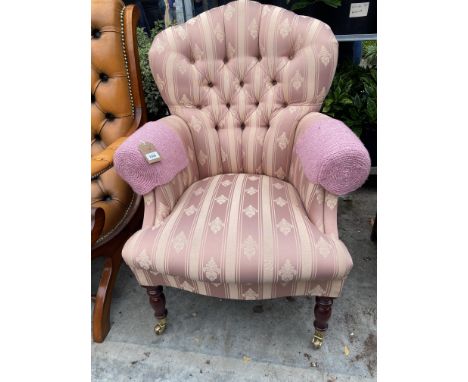 A VICTORIAN STYLE BUTTON-BACK LOUNGE CHAIR ON TURNED FRONT LEGS WITH BRASS CASTERS 