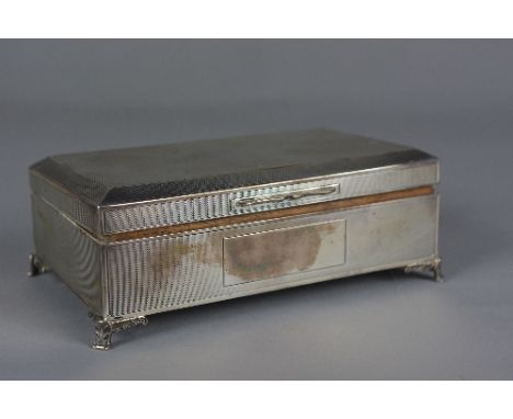 AN ELIZABETH II RECTANGULAR SILVER CIGARETTE BOX, engine turned decoration, blind cartouche, on four foliate scrolled bracket