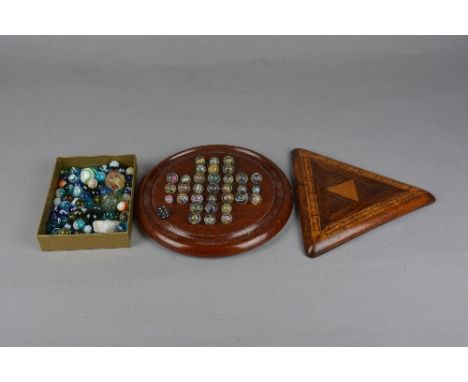 A VICTORIAN MAHOGANY SOLITAIRE BOARD, on three bun feet, diameter approximately 23.5cm, together with approximately 105 glass