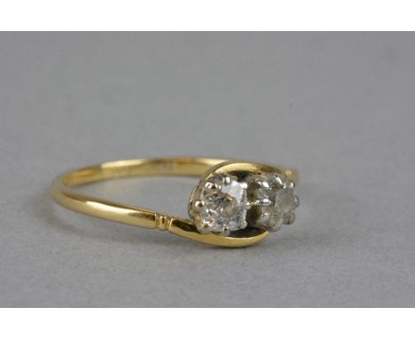 AN EARLY 20TH CENTURY TWO STONE DIAMOND CROSS OVER RING, two old cushion cut diamonds, estimated total weight 0.50ct, colour 