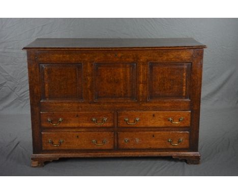 A GEORGE III OAK LANCASHIRE MULE CHEST, the plank top above a triple panel front and four short drawers, brass swan neck hand