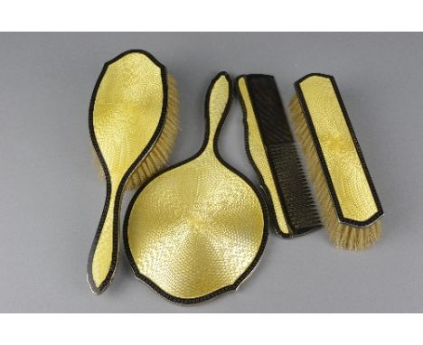 A GEORGE V SILVER AND YELLOW AND BLACK ENAMELLED FOUR PIECE DRESSING TABLE SET, engine turned decoration, comprising hand mir