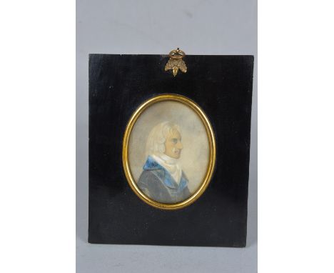 AN EARLY 19TH CENTURY PORTRAIT MINIATURE OF A GENTLEMAN, seated in profile, wearing a blue collared black coat, watercolour, 