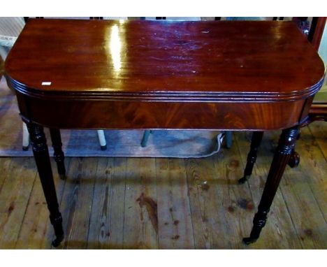 A Victorian mahogany fold-over card table on turned and fluted supports, terminating in brass castors.