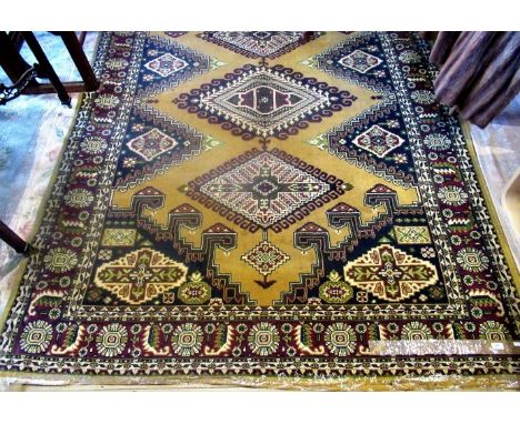 A large patterned carpet, the scroll and lozenge centre panel on a mustard ground with green and flower decoration on a red b