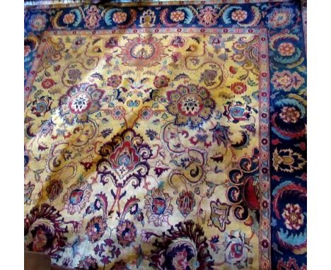 A large patterned carpet, the flowered central panel on a mustard ground, within a blue decorated border, 310 x 170cm. Condit