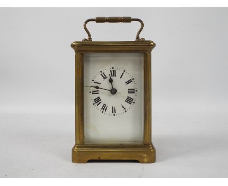An early 20th century brass and glass cased carriage timepiece clock, white enamel dial with Roman numerals with bevelled gla
