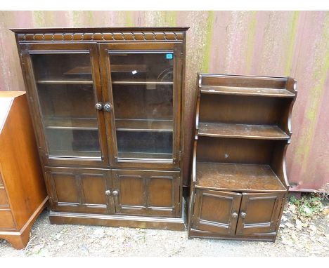 An Ercol dark elm a bookcase and waterfall bookcase with panelled cupboards below, A/F