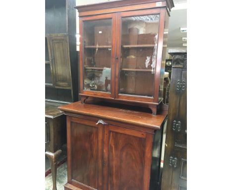 A late Victorian mahogany cabinet with a pair of glazed doors enclosing shelfs above cupboards on a plinth base. 91x46cm