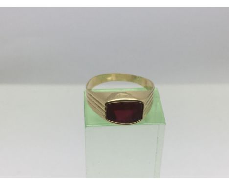 An unmarked gold ring with a red stone, approx 1.6g and approx size M.