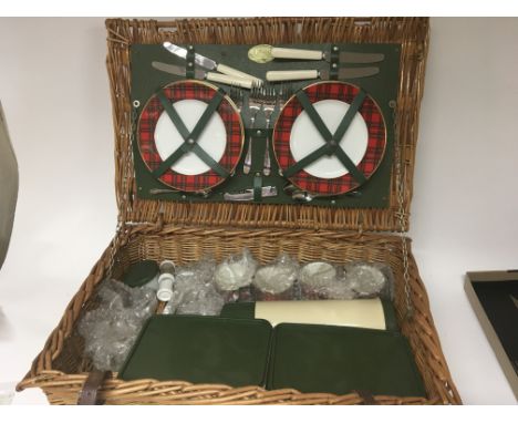 A Vintage Wicker Picnic hamper unused maker Optima England with tartan pattern plates and cups and green sandwich boxes.