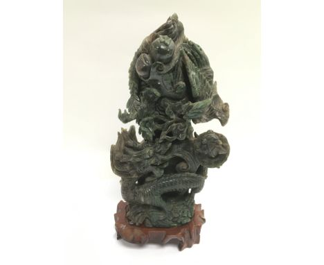 A carved jade ornament of a dragon raised on a hardwood stand, total approx height 23.5cm.