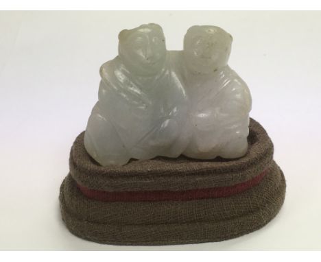 A small jade carving of two figures on a stand (not original), approx height of jade 4cm.