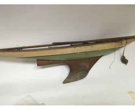 A large Vintage painted wood pond yacht with a weighted keel inset caring handle one mast and a boom. For restoration or disp