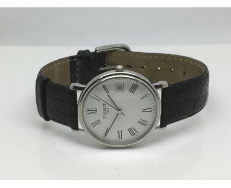 A gents Tissot watch with white face and date aperture on a black leather strap.