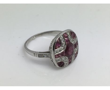 A Victorian style platinum panel ring set with a central oval cut ruby surrounded by diamonds and rubies, approx 4.3g and app