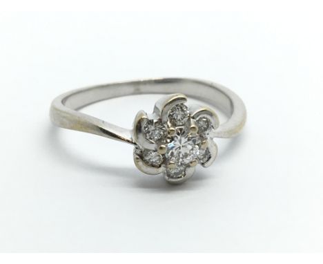 An 18ct white gold seven stone diamond ring in the form of a flowerhead, approx .20ct, approx 2.5g and approx size M.