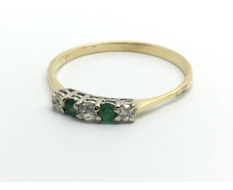 An unmarked yellow metal ring set with three small diamonds and two emeralds, approx 1.8g and approx size R-S.