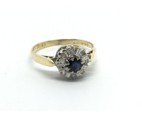 An 18carat gold ring set with a sapphire flanked by a round pattern of diamonds.Ring size K.