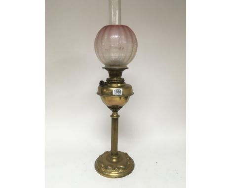 A brass oil lamp with an acid etched glass shade the base with raised decoration. Height 75cm