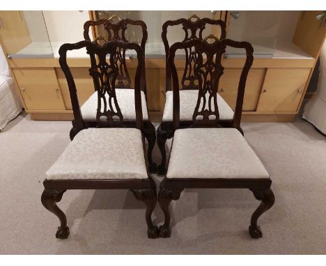 A set of four Chippendale carved dining chairs interlocking scroll lattice splats with clasped hand metal surmount, ball and 