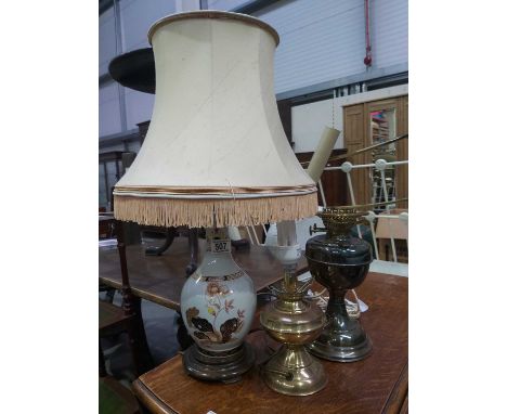 An Imari style porcelain table lamp, on turned wooden base, together with two oil lamps, converted (3)