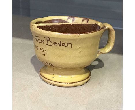 An Ewenny red stoneware claypits pottery shaving mug, yellow slip glaze, circular footed form with loop handle and half-shelf