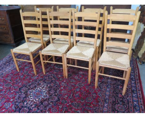A set of eight beech ladder back chairs with rush seats retailed by Heals