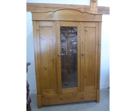 A Continental three door sectional pine wardrobe with fitted shelves and hanging, attractive shaped top and centre glass door