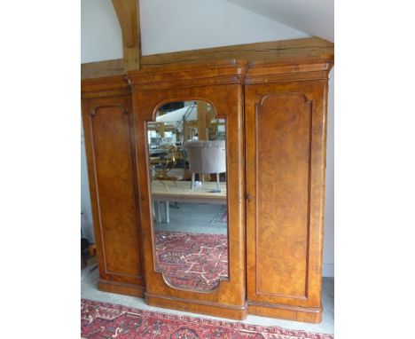 A Victorian burr walnut breakfront triple wardrobe with a central mirrored door enclosing slides and drawers flanked either s