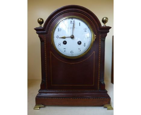 An eight day French mantel clock in a mahogany case with inlay, brass feet and finial's 
Condition report: Working with key 