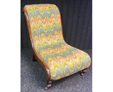 A Victorian Lounge chair, The Straw filled cushion upholstered in a multi colour covering within a scroll frame ending in cas